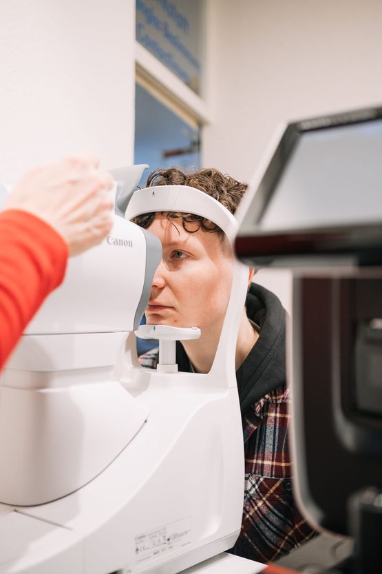 Ein Techniker verwendet in einer medizinischen Einrichtung ein Augenuntersuchungsgerät an einem Patienten und konzentriert sich dabei auf das Display und die Bedienelemente des Geräts.